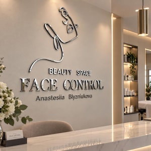Pode incluir: Uma placa de parede com um perfil de rosto em linha metálica prateada sobre o texto BEAUTY SPACE FACE CONTROL e o nome Anastesiia Blyzniukova em letras prateadas, fixada numa parede de tons neutros num espaço profissional.