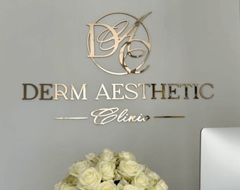 May include: A gold-coloured sign on a wall, reading "DERM AESTHETIC Clinic". The sign includes a circular logo and a line beneath the text. A bouquet of white roses is positioned below the sign, adding a touch of elegance.