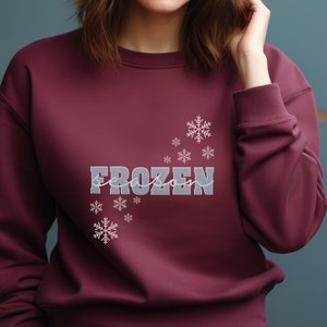 May include: A maroon sweatshirt with the text "FROZEN season" in white and gray lettering with a snowflake design.
