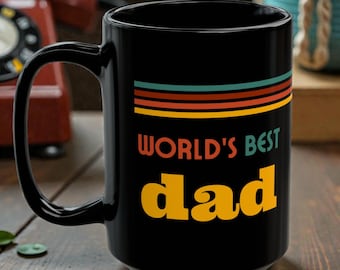 May include: A black ceramic mug with a large handle. The mug features the text "WORLD'S BEST dad" in yellow and a retro-style stripe design in orange, teal, and brown.