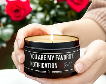 Könnte beinhalten: Eine schwarze Kerze mit dem Text "You are my favorite notification" und einem roten Herzen mit dem Namen "Rachel" daneben. Die Kerze ist angezündet und wird von einer Person in den Händen gehalten.