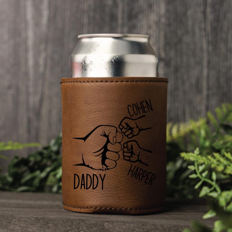 May include: Brown leather can cooler with a design of four fists bumping each other. The text "Daddy" is below the largest fist, "Cohen" is above the second largest fist, and "Harper" is below the smallest fist.