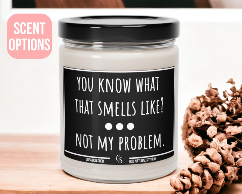 May include: A white candle with a black label that reads "You know what that smells like? Not my problem." The candle is 9 oz and made with natural soy wax.