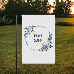 May include: A white garden flag with a blue and yellow floral wreath and the text "Jenny's Garden" in a black circle.