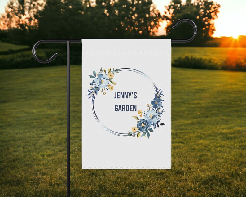 May include: A white garden flag with a blue and yellow floral wreath and the text "Jenny's Garden" in a black circle.