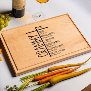 May include: A wooden cutting board with the word "GRAMMY" engraved on the side and a cross with bible verses about being chosen, made for a purpose, a child of God, equipped for battle, healed by his stripes, forgiven and set free.