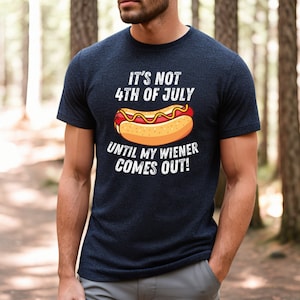Pode incluir: Uma camiseta azul marinho com um gr&aacute;fico branco de um cachorro-quente e o texto "It's not 4th of July until my wiener comes out!"