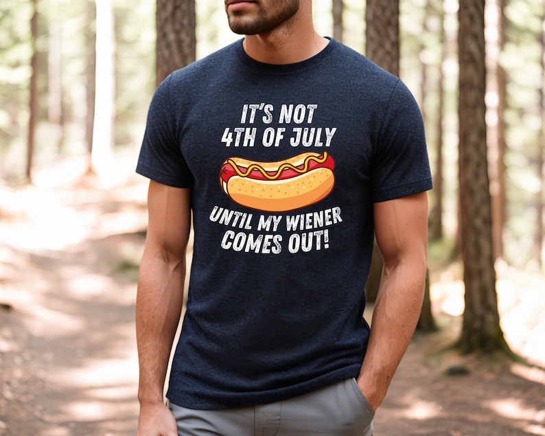 Pode incluir: Uma camiseta azul marinho com um gr&aacute;fico branco de um cachorro-quente e o texto "It's not 4th of July until my wiener comes out!"