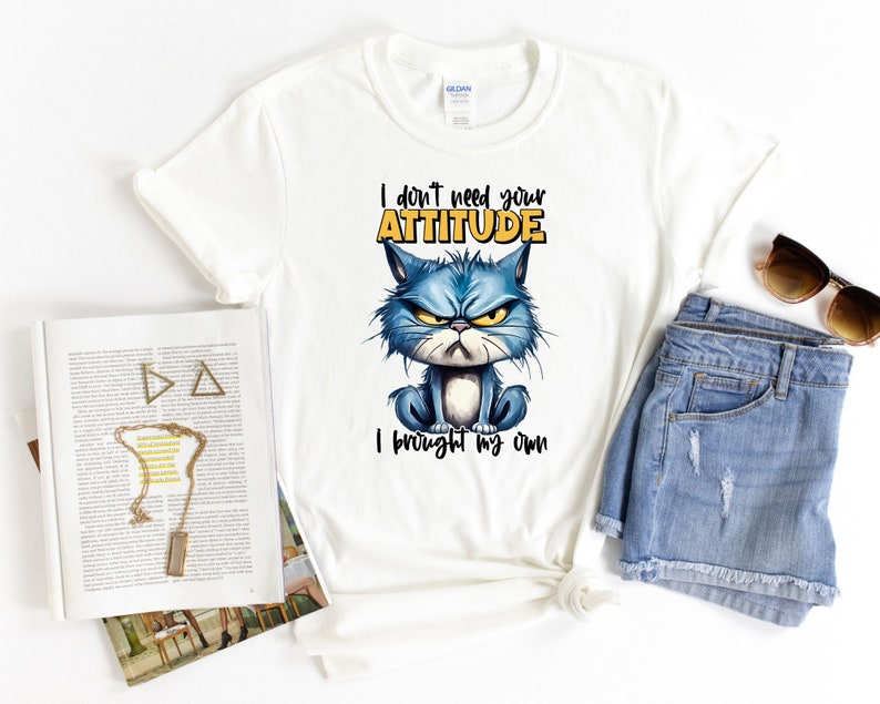 Op de afbeelding: Wit T-shirt met een blauwe cartoonkat en de tekst "Ik heb je houding niet nodig, ik heb mijn eigen".