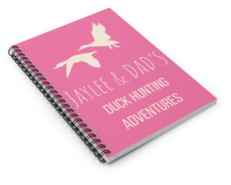 May include: Pink spiral bound notebook with the text "Jaylee & Dad's Duck Hunting Adventures" in white. The notebook features two white silhouettes of ducks flying.