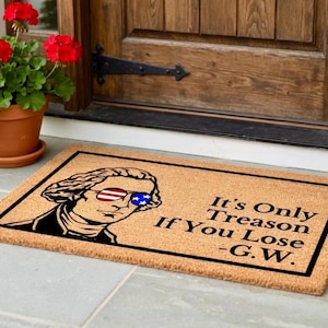 Peut inclure: Un paillasson rectangulaire avec une bordure noire et un fond beige. Le tapis pr&eacute;sente un graphique de George Washington portant des lunettes de soleil avec le design du drapeau am&eacute;ricain. Le texte se lit comme suit : "It's Only Treason If You Lose - G.W."