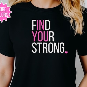 May include: Black t-shirt with the words "FIND YOUR STRONG" in white and pink lettering. A pink heart is at the end of the word "STRONG". A pink starburst graphic in the upper left corner says "MORE COLORS".
