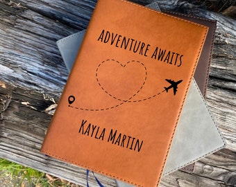 May include: A brown leather journal with the text "Adventure Awaits" and a heart shape with a plane flying out of it. The name "Kayla Martin" is written below the heart.