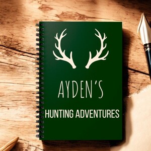 May include: A green spiral bound notebook with a white antler design and the text "AYDEN'S HUNTING ADVENTURES".