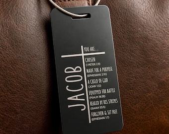 May include: A rectangular black metal luggage tag featuring the name JACOB in white vertical text. A white cross design incorporates the text YOU ARE... followed by CHOSEN, MADE FOR A PURPOSE, A CHILD OF GOD, EQUIPPED FOR BATTLE, HEALED BY HIS STRIPES, and FORGIVEN & SET FREE.