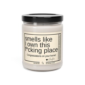 May include: A white candle jar with a black lid and a label that reads "smells like I own this f*cking place. Congratulations on your home!" The label also includes the text "Creation Shed" and "9oz Natural Soy Wax".