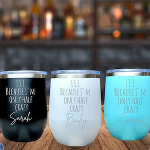 May include: Three stainless steel wine tumblers with a black, white, and blue finish. Each tumbler has a personalized inscription that reads "13.1 Because I'm Only Half Crazy" followed by a name: Sarah, Bailey, and Carson.