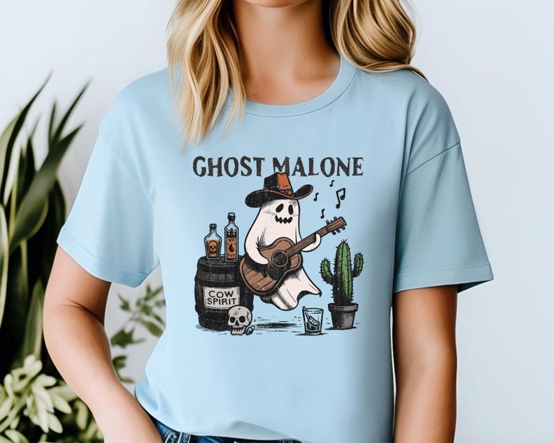 May include: A light blue t-shirt with a graphic of a ghost wearing a cowboy hat and playing a guitar. The text "Ghost Malone" is printed above the ghost.