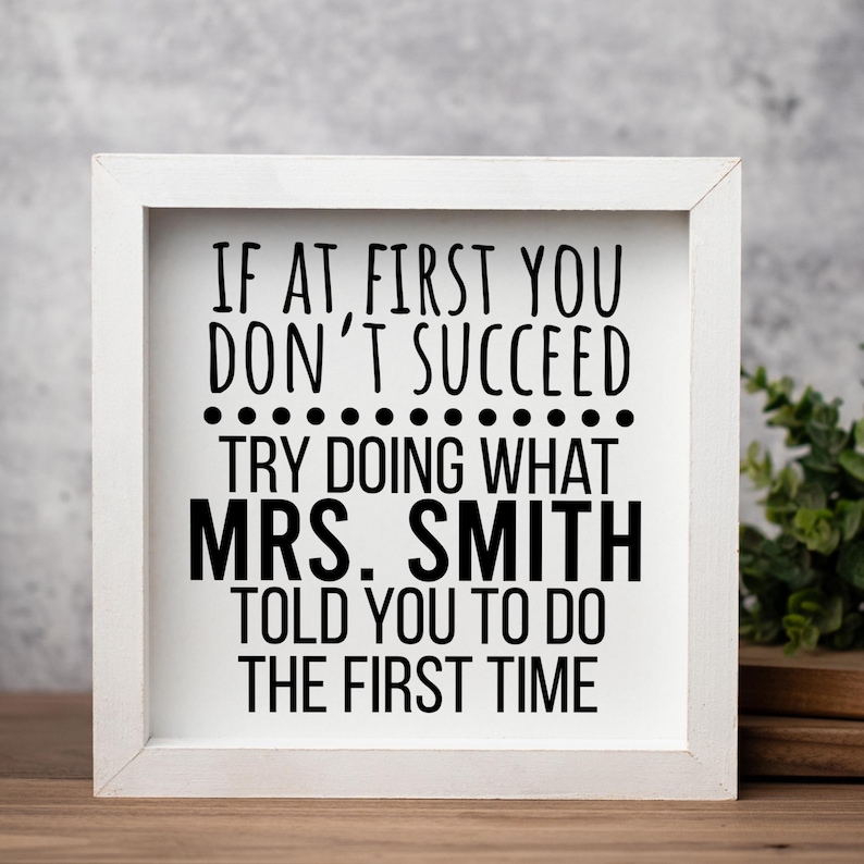 May include: A square wooden sign with a white frame and a white background featuring black text that reads: IF AT FIRST YOU DON'T SUCCEED TRY DOING WHAT MRS. SMITH TOLD YOU TO DO THE FIRST TIME. The sign has a clean, simple design.