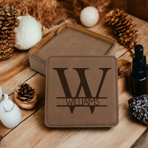 May include: A brown leather coaster with a large initial "W" and the name "Williams" engraved in a black font.