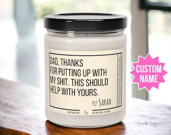 May include: A white candle with a black lid and a cream label that reads "DAD, THANKS FOR PUTTING UP WITH MY SHIT. THIS SHOULD HELP WITH YOURS. SARAH". The candle is on a wooden surface. Hand Poured in the US - Natural Soy Wax. Creation Shed shop - creationshedshop.etsy.com