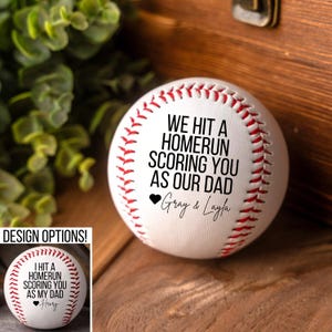 May include: White baseball with black text that reads "We hit a homerun scoring you as our dad" with a heart and the names "Gray & Layla".