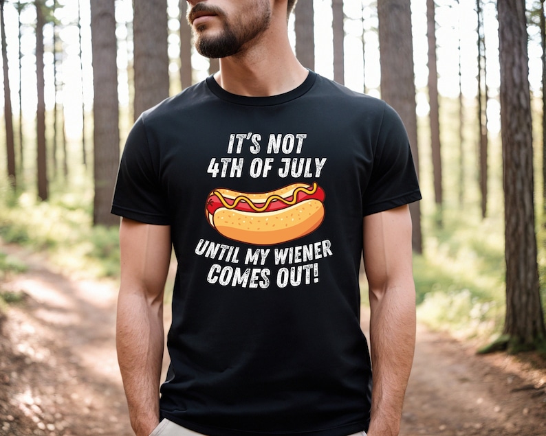 Pode incluir: Uma camiseta preta com um gr&aacute;fico branco de um cachorro-quente e o texto "N&atilde;o &eacute; 4 de julho at&eacute; que meu wiener saia!"