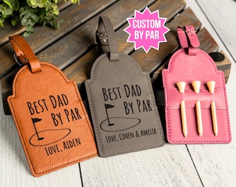 May include: Three leather luggage tags with the text "Best Dad By Par" and a golf club graphic. The tags are brown, gray, and pink. The pink tag has a pocket for golf tees.