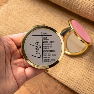 Peut inclure: Un miroir compact dor&eacute; avec un fond blanc et du texte noir. Le texte dit "You are... Chosen (1 Peter 2:9) Made for a Purpose (Ephesians 2:10) A Child of God (John 1:12) Equipped for Battle (Psalm 18:39) Healed by His Stripes (Isaiah 53:5) Forgiven & Set Free (Ephesians 1:7)". Le nom "Laela" est &eacute;crit en cursive sur le miroir.