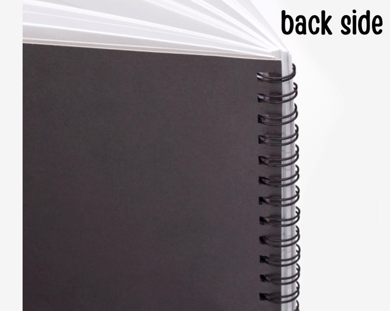May include: The back side of a black spiral bound notebook. The notebook has a black cover and a silver spiral binding.