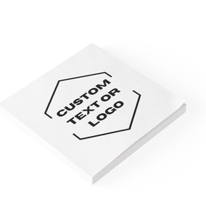 以下が含まれることがあります： 黒い六角形の中に「CUSTOM TEXT OR LOGO」というテキストが書かれた、白い正方形の付箋紙パッドです。