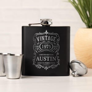 May include: Black stainless steel flask with a silver screw-on cap. The flask is engraved with the words "VINTAGE 1975 LIMITED EDITION AUSTIN AGED TO PERFECTION". Includes two small silver shot glasses and a funnel.