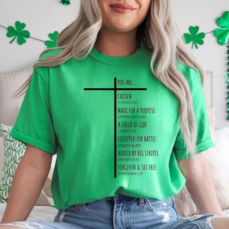 May include: Green t-shirt with a black cross and the text "YOU ARE... CHOSEN (1 PETER 2:9) MADE FOR A PURPOSE (EPHESIANS 2:10) A CHILD OF GOD (JOHN 1:12) EQUIPPED FOR BATTLE (PSALM 18:39) HEALED BY HIS STRIPES (ISAIAH 53:5) FORGIVEN & SET FREE (EPHESIANS 1:7)"