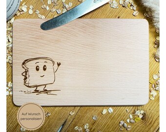 May include: A wooden cutting board with a cartoon drawing of a smiling slice of bread with arms and legs. The text "Auf Wunsch personalisiert" is printed on the board.