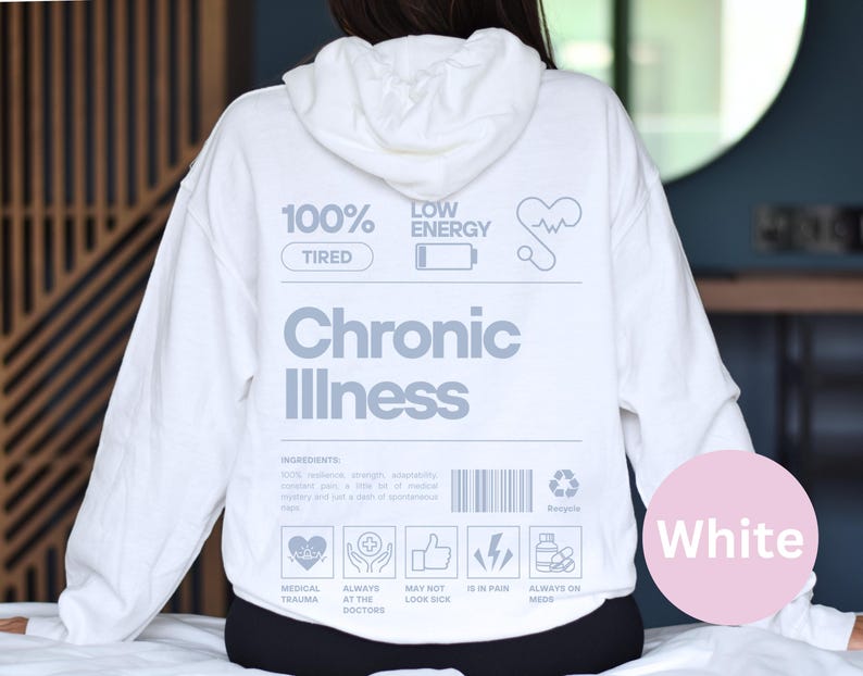 May include: White hoodie with the text "100% Tired" and "Low Energy" on the front. The text "Chronic Illness" is printed in large letters below the text. The hoodie has a graphic of a heart with a heartbeat line, a battery icon, and a recycling symbol. The text "Medical Trauma", "Always at the Doctors", "May Not Look Sick", "Is in Pain", and "Always on Meds" is printed below the graphic.