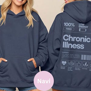 May include: A navy blue hooded sweatshirt with a large white graphic on the back that reads "100% Tired, Low Energy, Chronic Illness". The graphic is a parody of a product label with a list of ingredients and warnings.