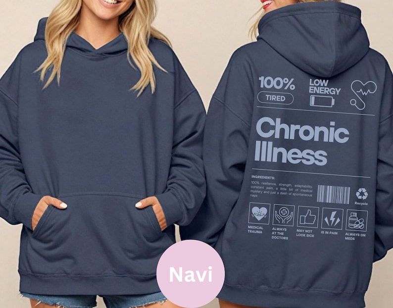May include: A navy blue hooded sweatshirt with a large white graphic on the back that reads "100% Tired, Low Energy, Chronic Illness". The graphic is a parody of a product label with a list of ingredients and warnings.
