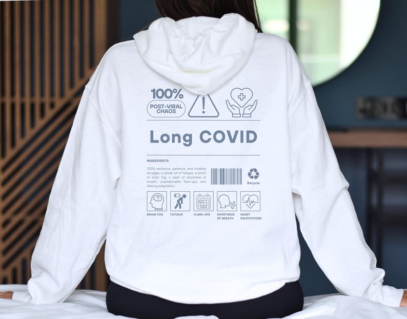 May include: White hoodie with the words "Long COVID" and other text and icons. The hoodie has a drawstring hood and long sleeves. The back of the hoodie features a list of symptoms and a recycle symbol.