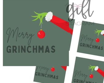 Könnte beinhalten: Vier druckbare Geschenkanhänger mit einer grünen Grinch-Hand, die einen roten Weihnachtsbaumschmuck hält. Der Text auf den Anhängern lautet "Frohe Grinchmas".