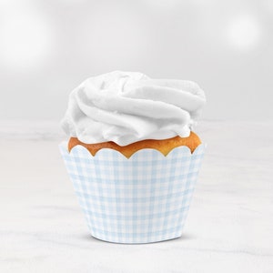 Può includere: Un singolo cupcake con glassa bianca e un pirottino per cupcake a quadri blu e bianchi.