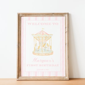 May include: A pink and white printable sign with a gold frame. The sign says "Welcome to [Name]'s First Birthday" with a picture of a carousel horse.