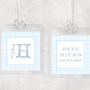 May include: Two clear luggage tags with blue gingham borders. One tag features the initials "JPH" in a light blue watercolor font. The other tag displays the name "Pate Hicks" and a phone number in a similar font.