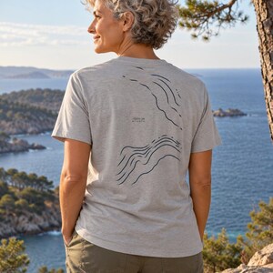 K&ouml;nnte beinhalten: Ein hellgraues Kurzarm-T-Shirt mit einem dunkelblauen Grafikdruck topografischer Linien auf der R&uuml;ckseite. Der Druck enth&auml;lt den Text -1200 m ATLANTIC. Das T-Shirt hat einen Rundhalsausschnitt und eine Standardpassform aus meliertem Stoff.