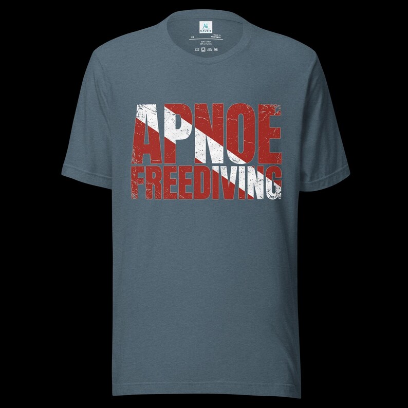 Puede incluir: Una camiseta de manga corta color azul pizarra con un estampado gr&aacute;fico desgastado en rojo y blanco. El dise&ntilde;o muestra el texto APNOE FREEDIVING superpuesto sobre un patr&oacute;n de rayas diagonales rojas y blancas, similar a una bandera de buceo.