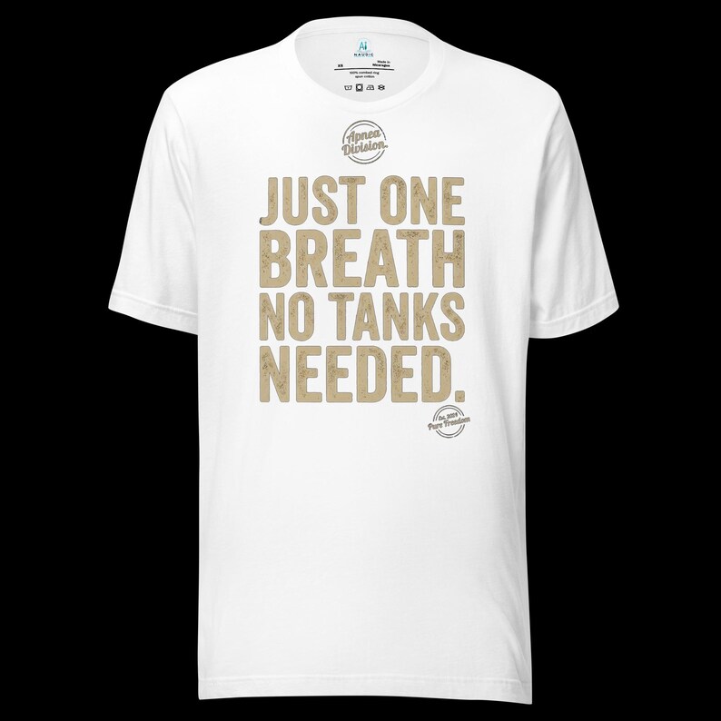 May include: A white short-sleeve t-shirt featuring the text "JUST ONE BREATH NO TANKS NEEDED." in a distressed tan font. Above the text is a circular "Apnea Division" logo, and below the text is a smaller circular "Est. 2019 Pure Freedom" logo.
