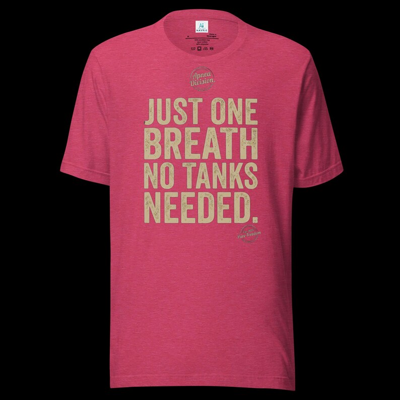 May include: A heathered red short-sleeve t-shirt featuring the text "JUST ONE BREATH NO TANKS NEEDED." printed in a distressed beige font on the chest. The shirt includes a small circular logo above the text and a brand label at the inner neck.