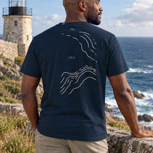 K&ouml;nnte beinhalten: Ein dunkelblaues Kurzarm-T-Shirt mit einer wei&szlig;en Strichgrafik auf der R&uuml;ckseite. Das Design zeigt abstrakte topografische Wellenmuster und enth&auml;lt den aufgedruckten Text -1200 m ATLANTIC zwischen den beiden Wellenillustrationen.