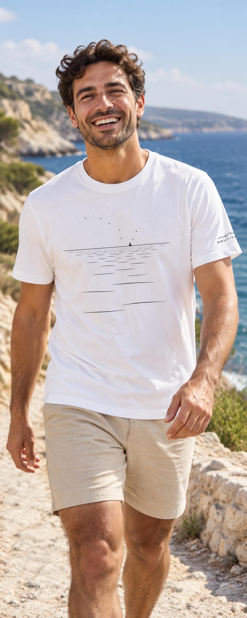 Peut inclure: Un t-shirt blanc &agrave; manches courtes orn&eacute; d'un graphisme au trait noir repr&eacute;sentant un horizon marin calme avec un petit voilier et des &eacute;toiles. La manche gauche porte l'inscription NAUTIY en noir avec une petite ic&ocirc;ne de vague au-dessus.