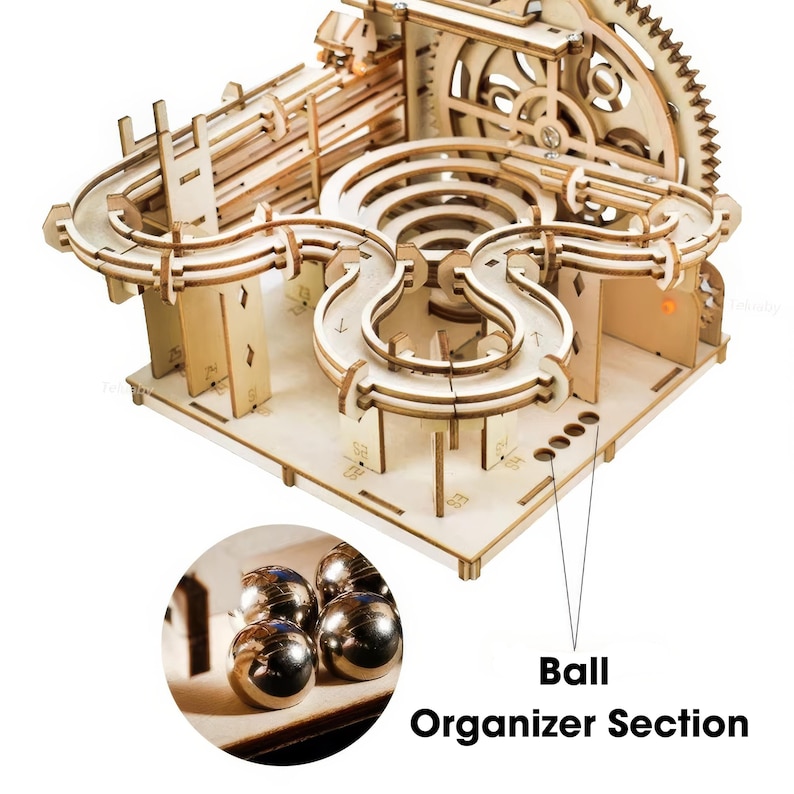 May include: A wooden marble run kit with a complex track design, featuring multiple loops, gears, and a ball organizer section. The kit is made of light-colored wood and includes several metal marbles.