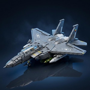 May include: A gray model fighter jet constructed from building blocks, featuring a clear cockpit canopy, dual vertical stabilizers, and mounted missiles under the wings. The aircraft displays printed star insignias and numerical markings.